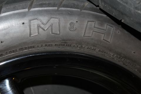 2003 Ford Crown Victoria - close-up of a drag tire sidewall embossed with the M&H logo and ply construction lettering on a black wheel.