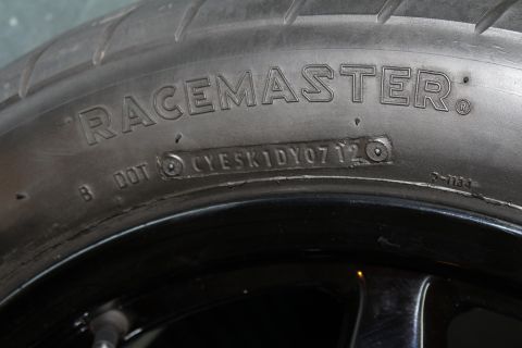 2003 Ford Crown Victoria - close-up of a tire sidewall embossed RACEMASTER with a DOT code stamp, mounted on a black wheel.