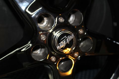 2003 Ford Crown Victoria - close-up of a glossy five-spoke wheel center showing lug holes and a center cap with a Race Star star logo.