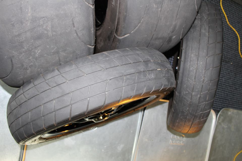 Several wide treaded drag tires piled together on the floor