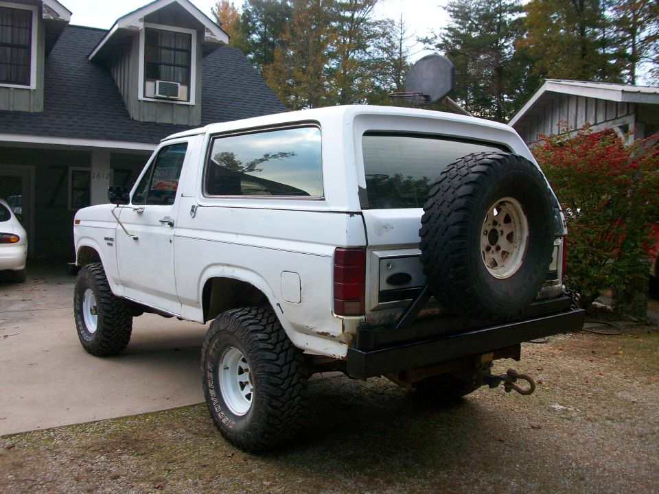 White Ford Bronco with spare tire mounted on rear bumper, seen from a 3/4 rear angle