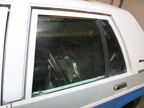 1991 Ford Crown Victoria LTD - The rear passenger side of a Ford Crown Victoria is visible, with the window frame and part of the door handle.