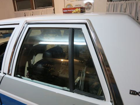 1991 Ford Crown Victoria LTD - Close-up view of the rear passenger side window and chrome trim of a white vehicle.