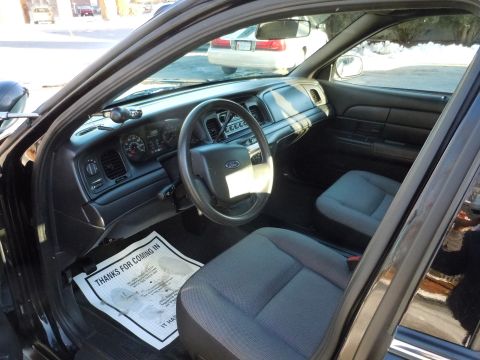 2001 Ford Crown Victoria - The interior of a 2001 Ford Crown Victoria police car is visible, including the dashboard, steering wheel, and front seats.