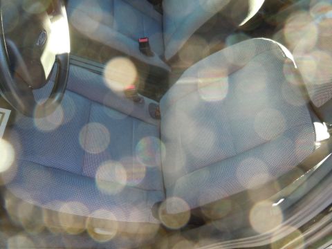 2001 Ford Crown Victoria - The interior of a car is visible, with a focus on the front seats and steering wheel, illuminated by sunlight.