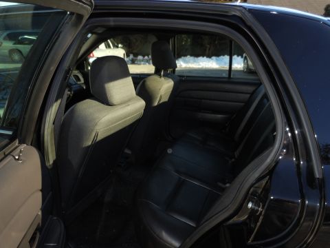 2001 Ford Crown Victoria - Interior view of the rear seating area of a dark-colored sedan, showing black leather seats and door trim.
