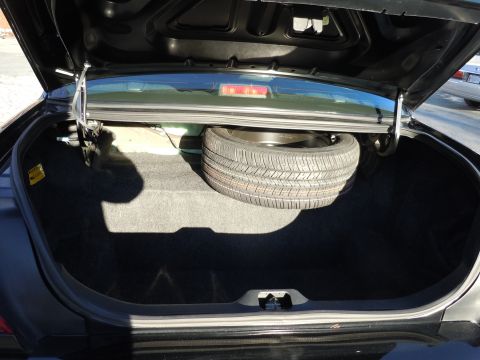 2001 Ford Crown Victoria - The trunk of a 2001 Ford Crown Victoria contains a spare tire and is lined with dark carpet.