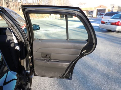 2001 Ford Crown Victoria - The interior door panel and open rear door of a 2001 Ford Crown Victoria are visible, with another car in the background.