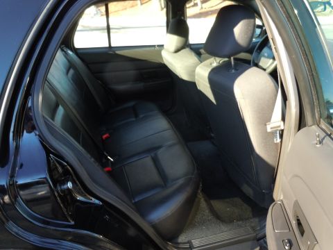 2001 Ford Crown Victoria - Rear interior view of a 2001 Ford Crown Victoria, highlighting the black leather seats and door trim.
