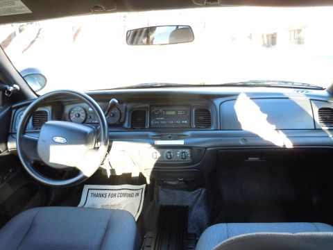 2001 Ford Crown Victoria - The interior of a 2001 Ford Crown Victoria shows the dashboard, steering wheel, and a floor mat with text.