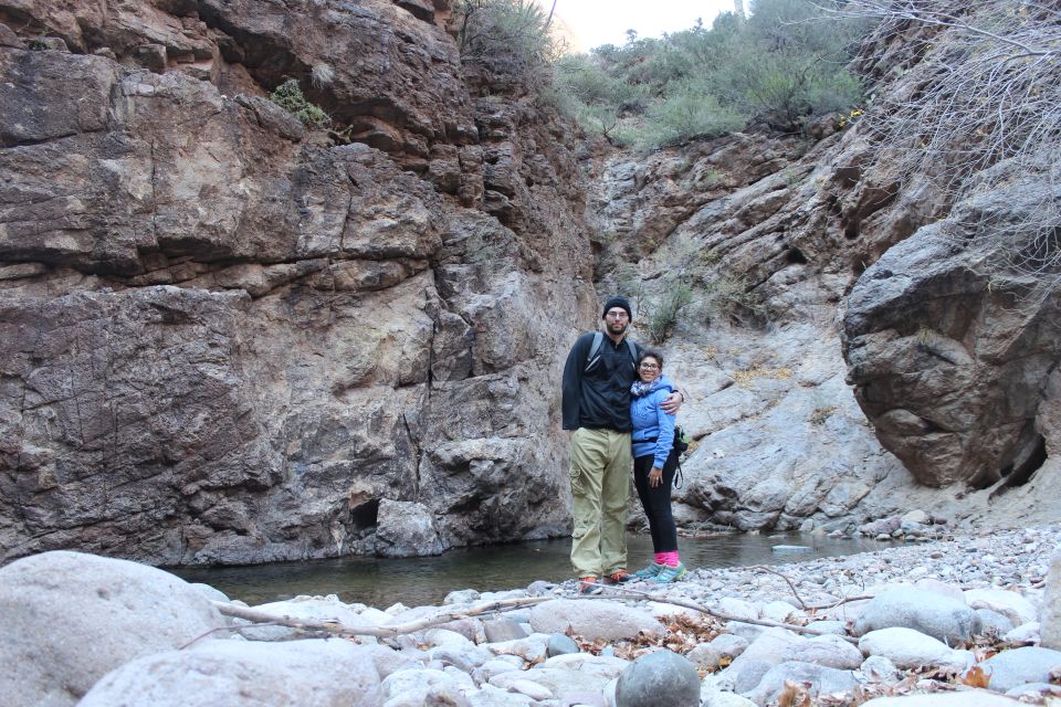 Couple standing in a rocky canyon next to a stream.