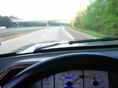 1988 Ford Bronco - View from the driver's seat of a vehicle on a highway, looking forward through the windshield. The dashboard and steering wheel are visible…