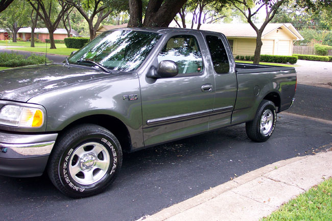 Gray 2003 Ford F-150 pickup truck, driver side view, parked on asphalt driveway