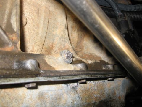 1988 Ford Bronco - A close-up view of a bolt in the engine block of a 1988 Ford Bronco. The engine block is dirty and appears to have some oil residue.