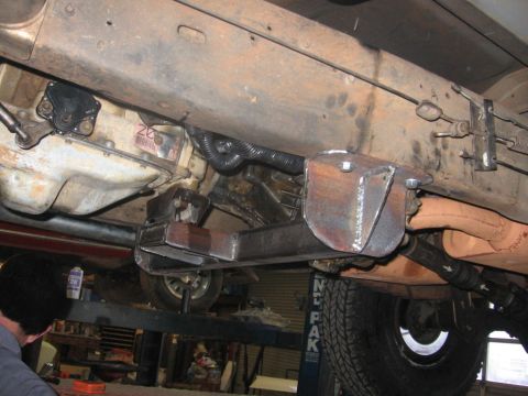 1988 Ford Bronco - Underside view of a vehicle's drivetrain, showing a transmission, custom fabricated metal support brackets, exhaust pipe, and driveshaft. T…