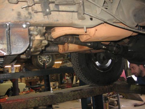 1988 Ford Bronco - The underside of a vehicle is shown on a lift, with a focus on the drivetrain components including the transmission, driveshaft, and differ…