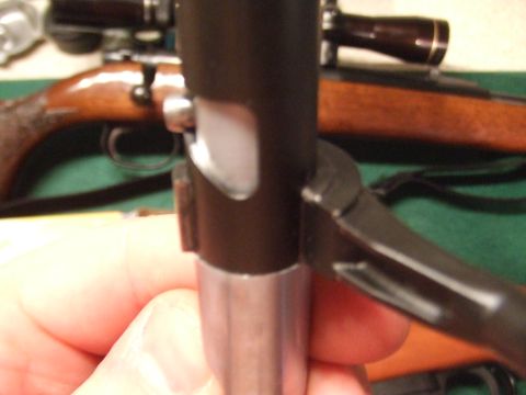 1996 Ford Bronco - A close-up shot focuses on a firearm's bolt action mechanism and trigger assembly, with a wooden rifle stock and scope visible in the blurr…