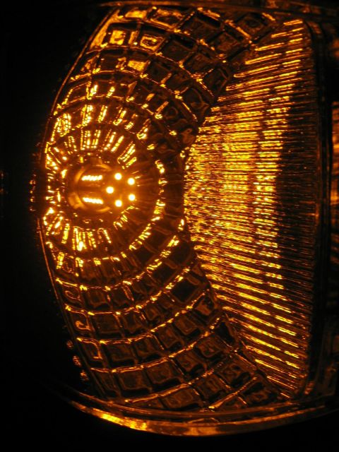 1988 Ford Bronco - A close-up, abstract view of an amber-colored vehicle light with a textured lens and illuminated bulbs within. The light appears to be part…