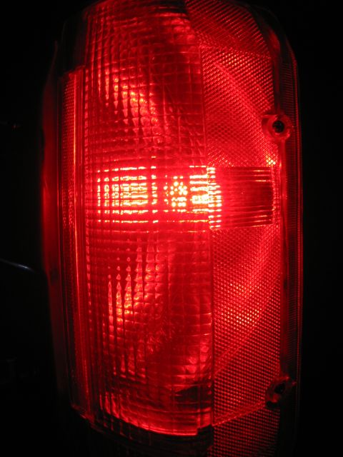 1988 Ford Bronco - A close-up, illuminated shot of a red taillight assembly on a vehicle, likely a Ford Bronco, against a dark background.