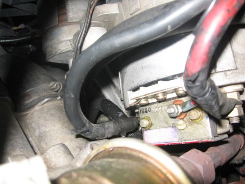 1988 Ford Bronco - A close-up view of a vehicle's electrical component, likely part of the alternator or voltage regulator, showing wiring, bolts, and some te…