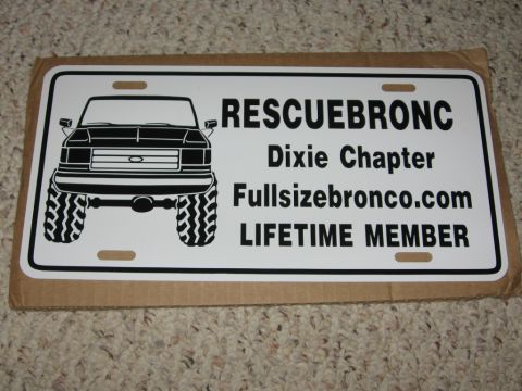 1988 Ford Bronco - A white license plate with black text and a black silhouette of a truck is displayed on a textured surface. The text reads "RESCUEBRONC Dix…