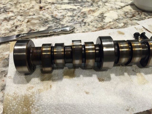 Close-up of a camshaft with lobes and bearing surfaces on a paper towel.