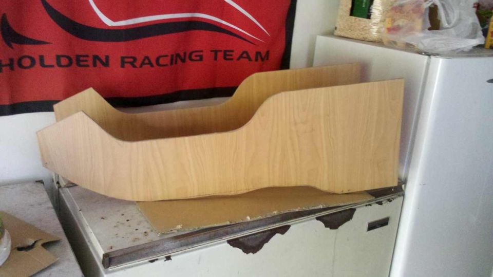 Wooden console insert on top of a metal surface, with a red Holden Racing Team banner in the background