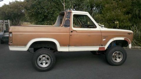 1982 Ford Bronco - Side profile of a lifted Ford Bronco, showing its two-tone paint and off-road tires.
