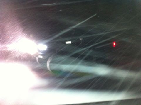 1988 Ford Bronco - A dark SUV navigates through snowy conditions, its headlights cutting through the blizzard.