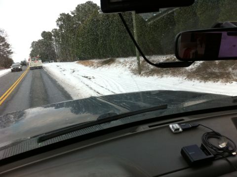 1988 Ford Bronco - Driving on a snowy road with other vehicles visible ahead and snow falling.