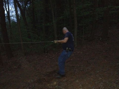 1988 Ford Bronco - A man is pulling a rope taut in a dimly lit forest setting.