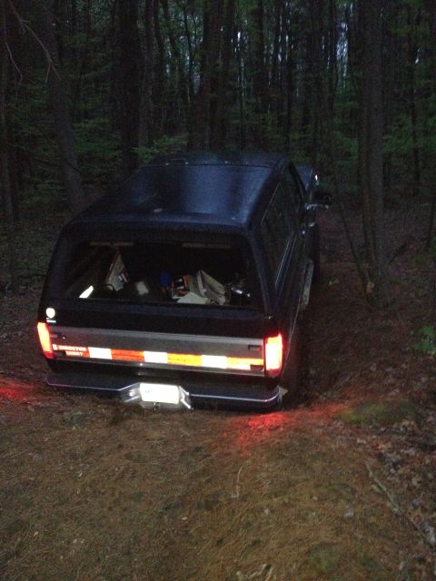1988 Ford Bronco - Black 1988 Ford Bronco is parked on a dirt path surrounded by trees.