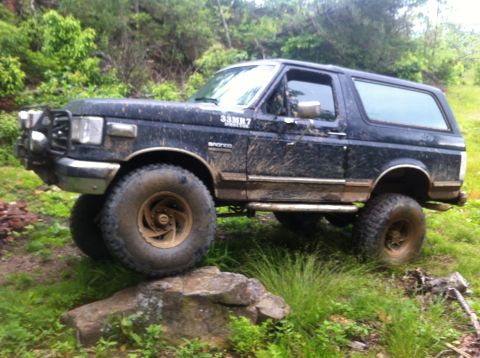 1988 Ford Bronco - This modified Ford Bronco is shown off-road, with its tires positioned on a large rock.