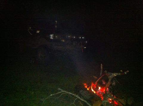 1988 Ford Bronco - A 1988 Ford Bronco is seen at night with a campfire burning nearby.