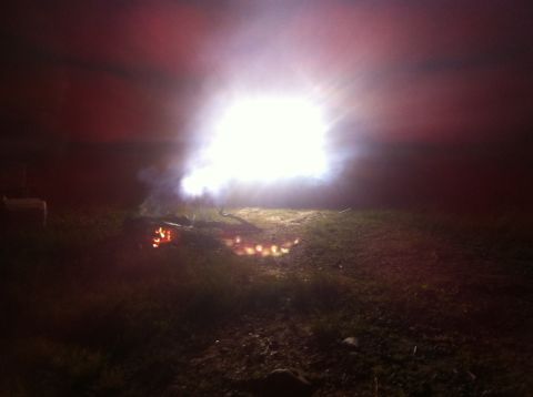 1988 Ford Bronco - A nighttime scene features a bonfire with flames and smoke illuminated by a bright light source.