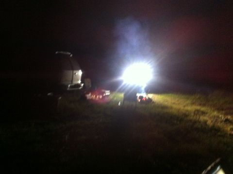 1988 Ford Bronco - Several vehicles are visible at night, illuminated by a very bright light source.