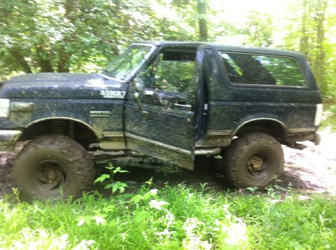 1988 Ford Bronco - This 1988 Ford Bronco is deep in the mud, with its driver's door ajar.