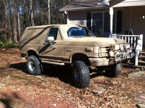 1988 Ford Bronco - Mud-covered 1988 Ford Bronco with auxiliary lights mounted on the front bumper.