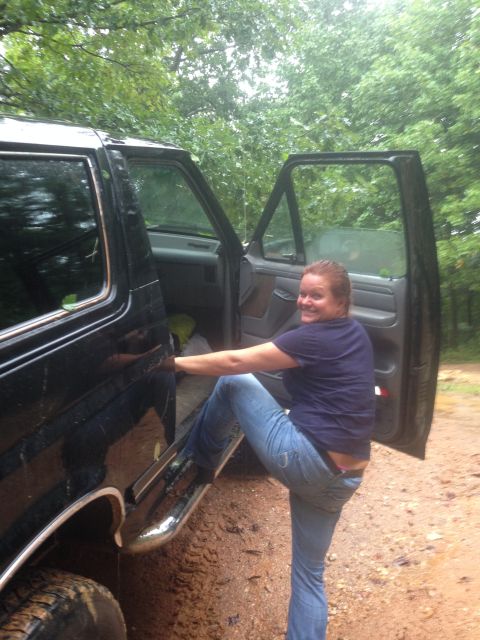 1988 Ford Bronco - A woman climbs into a black SUV with both doors open, parked off-road.