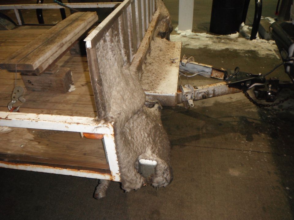 Trailer hitch and frame with wooden planks and insulation. White metal, some rust visible