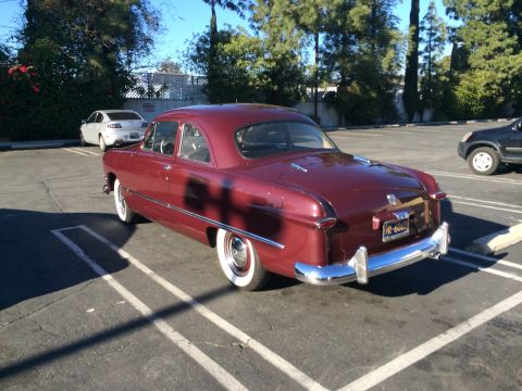 1968 Ford Mustang - This 1950 Ford Custom Deluxe coupe is parked in a lot with other vehicles present.