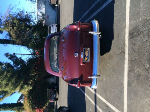 1968 Ford Mustang - Rear view of a vintage maroon sedan parked in a lot, showing its chrome bumper and taillights.