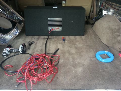 1994 Ford Bronco - Tools and a subwoofer are laid out in the cargo area of a vehicle, suggesting audio system installation.