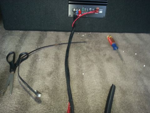 1994 Ford Bronco - Photo of a car-audio amplifier wiring harness and power cable run across trunk carpet.