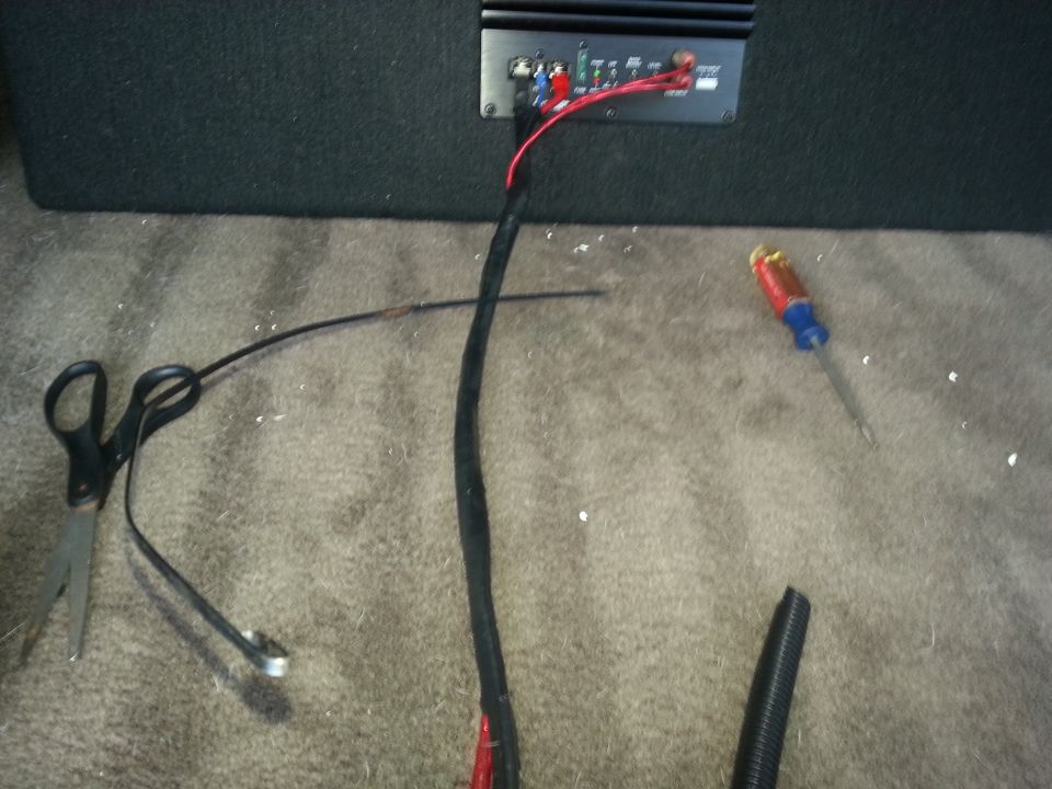 Amplifier wiring harness and cable run laid across trunk carpet with tools