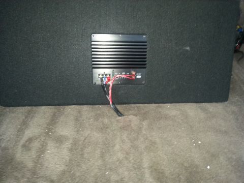 1994 Ford Bronco - Photo of the rear of a carpeted subwoofer box showing the amplifier plate and connected wiring.