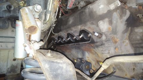 1995 Ford Bronco - A close-up view of the engine block of a 1995 Ford Bronco shows a set of four exhaust manifold bolts with a new manifold installed. A spark…