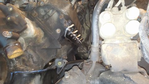 1995 Ford Bronco - A close-up view of an engine bay shows a modified fuel pressure regulator mounted to the engine block. Various hoses and rusted metal compo…