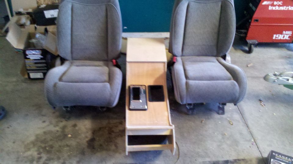Two gray car seats with a wooden console between them.
