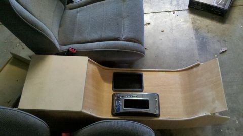 1982 Ford Bronco - Wood-trimmed center console with a stereo bracket removed and set on the floor next to a cloth bucket seat.